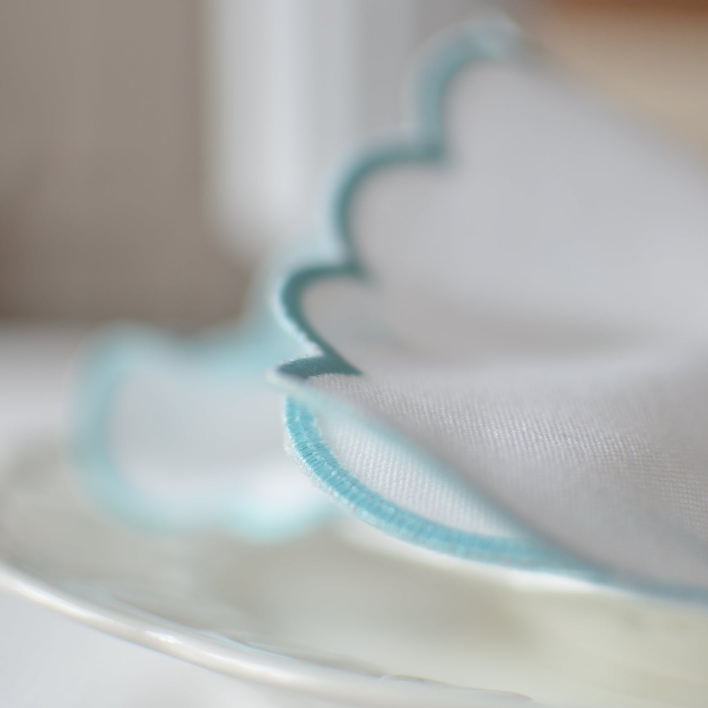 White cotton napkin with a turquoise scalloped edge