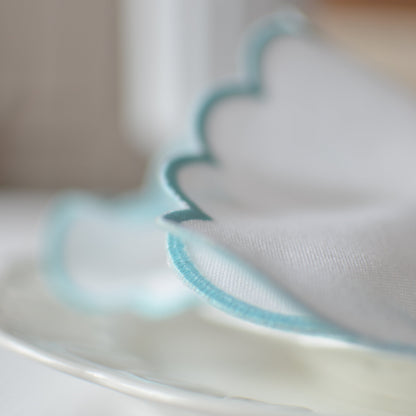 White cotton napkin with a turquoise scalloped edge