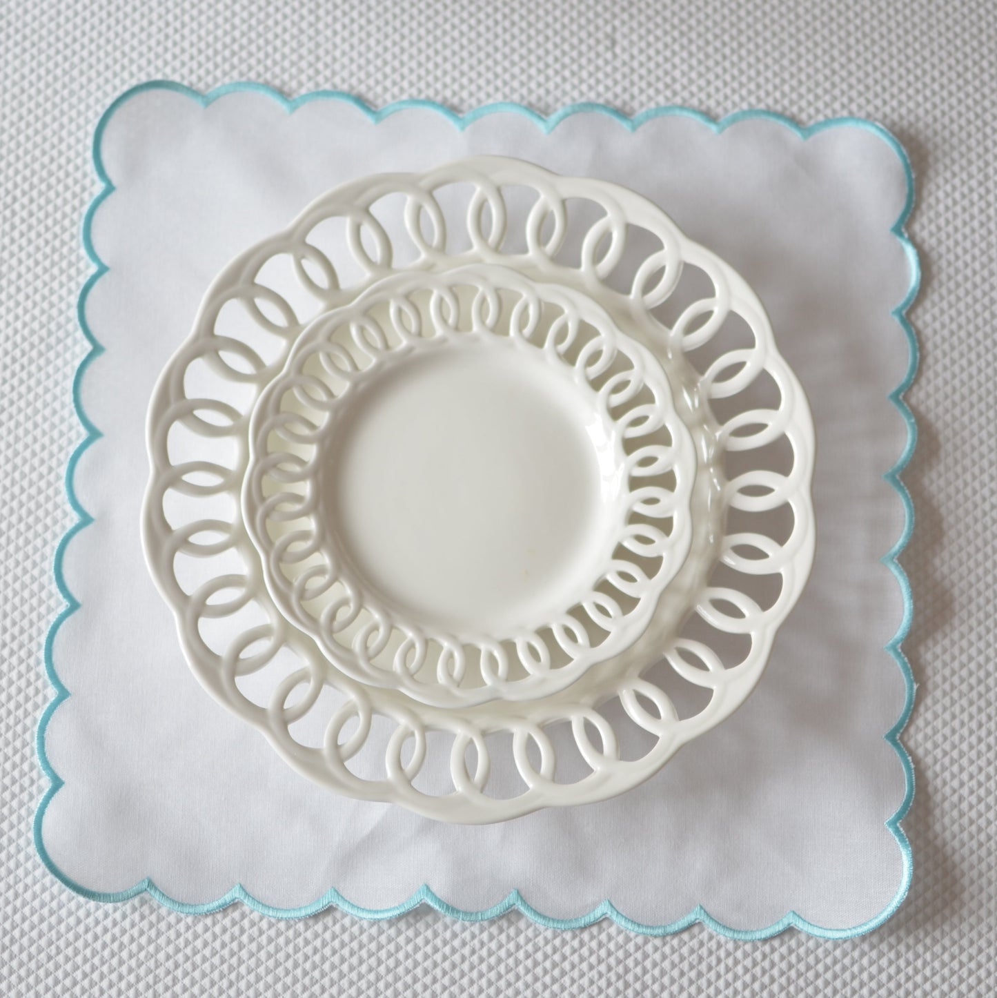 White cotton napkin with a turquoise scalloped edge