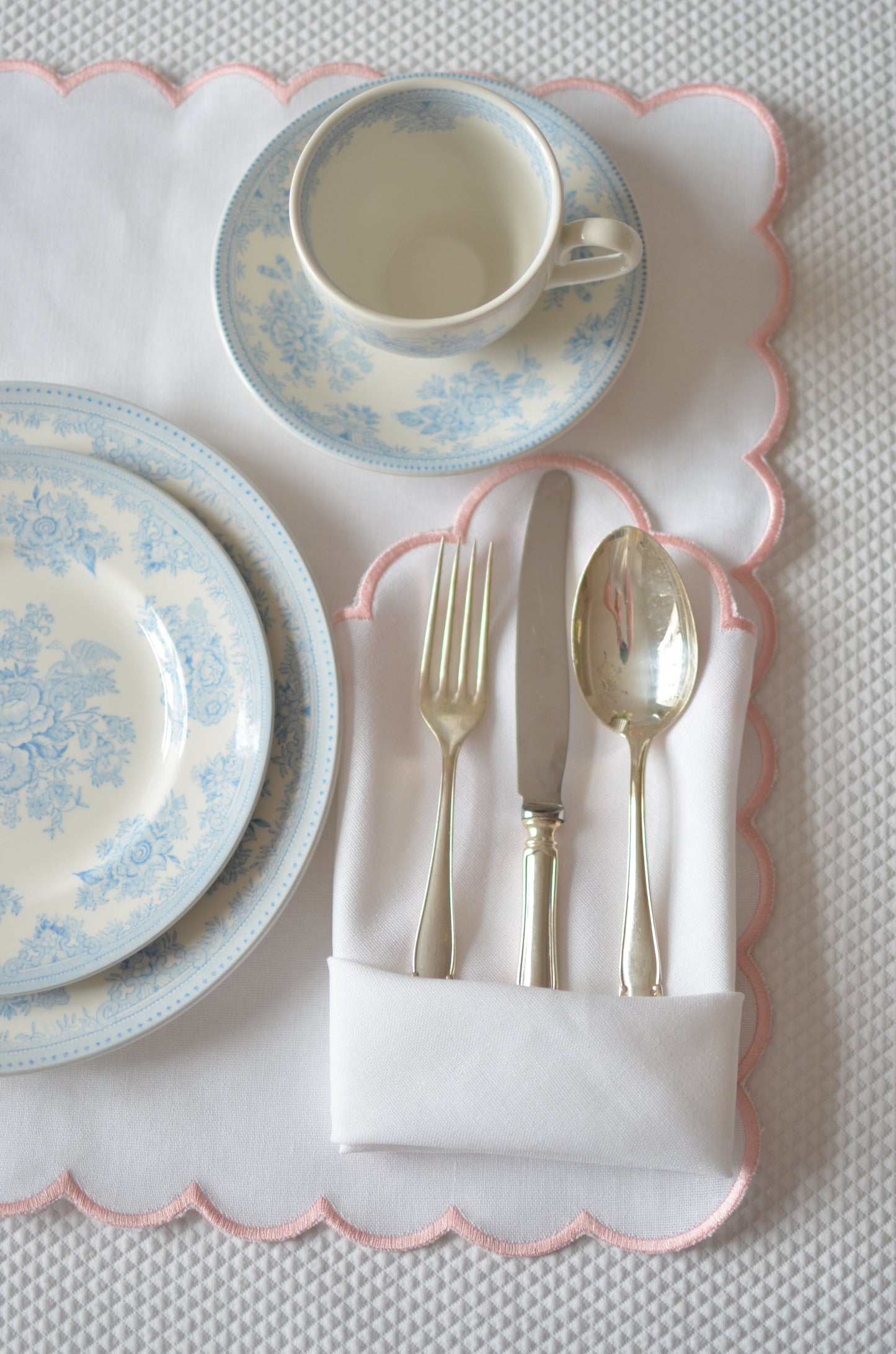 White cotton napkin with a pink scalloped edge