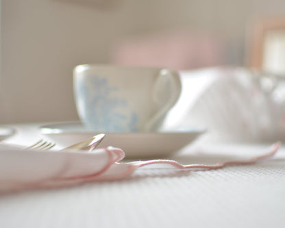 White cotton napkin with a pink scalloped edge