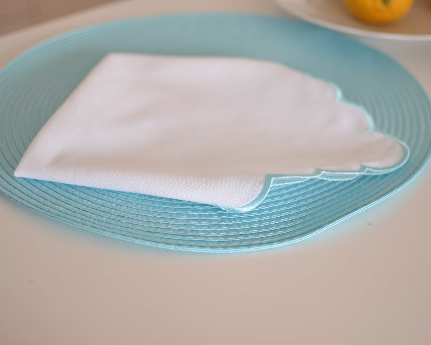 White cotton napkin with a turquoise scalloped edge
