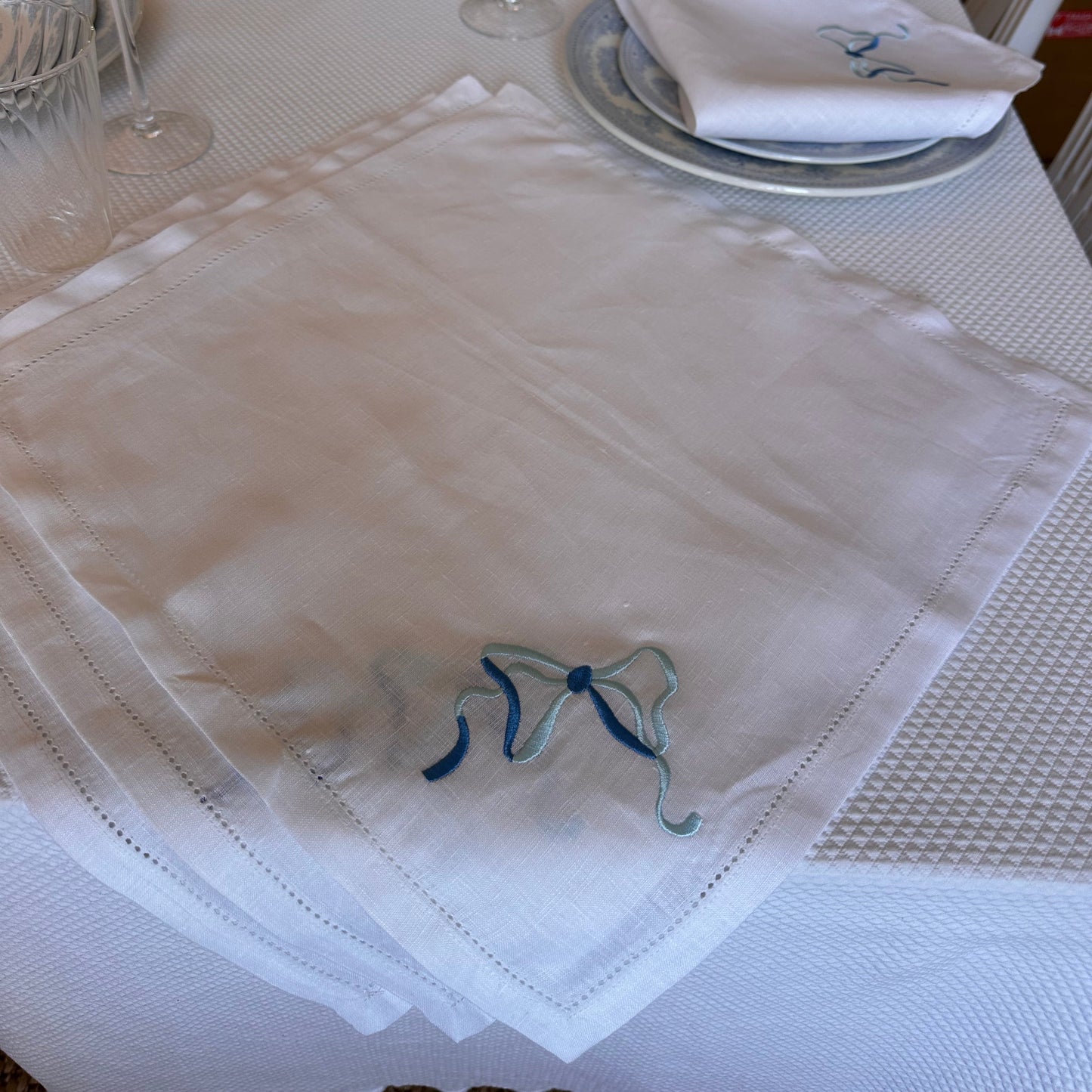 White linen napkin with a monogrammed blue bow