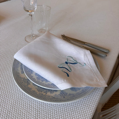White linen napkin with a monogrammed blue bow
