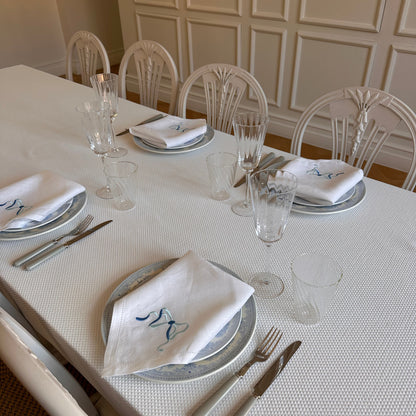 White linen napkin with a monogrammed blue bow