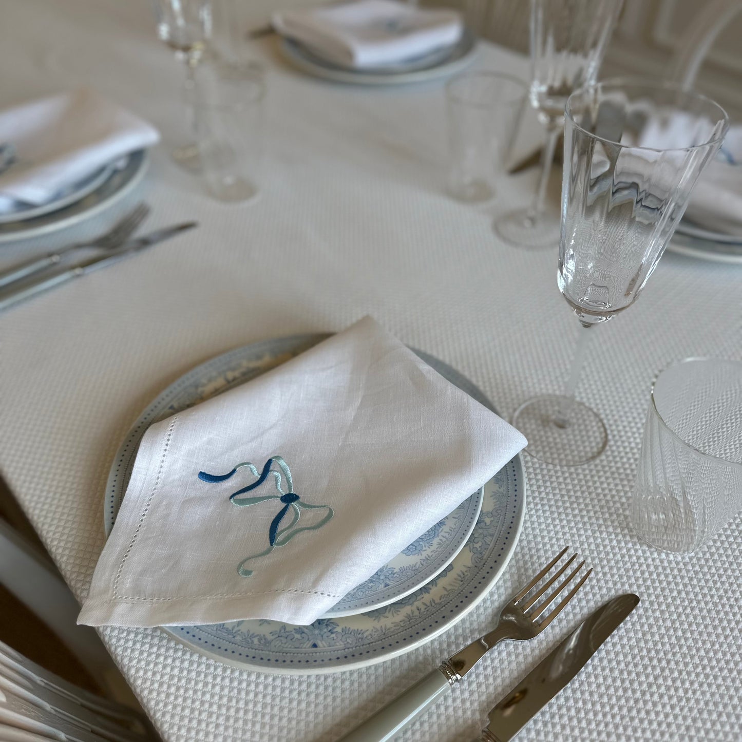 White linen napkin with a monogrammed blue bow