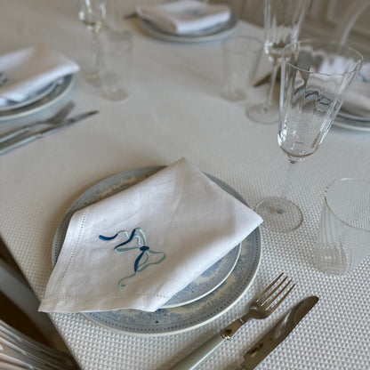 White linen napkin with a monogrammed blue bow