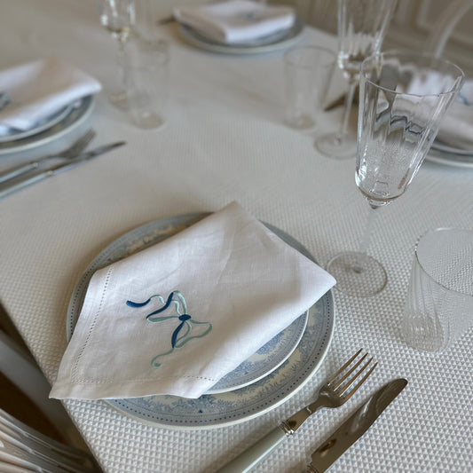 White linen napkin with a monogrammed blue bow