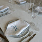 White linen napkin with a monogrammed blue bow