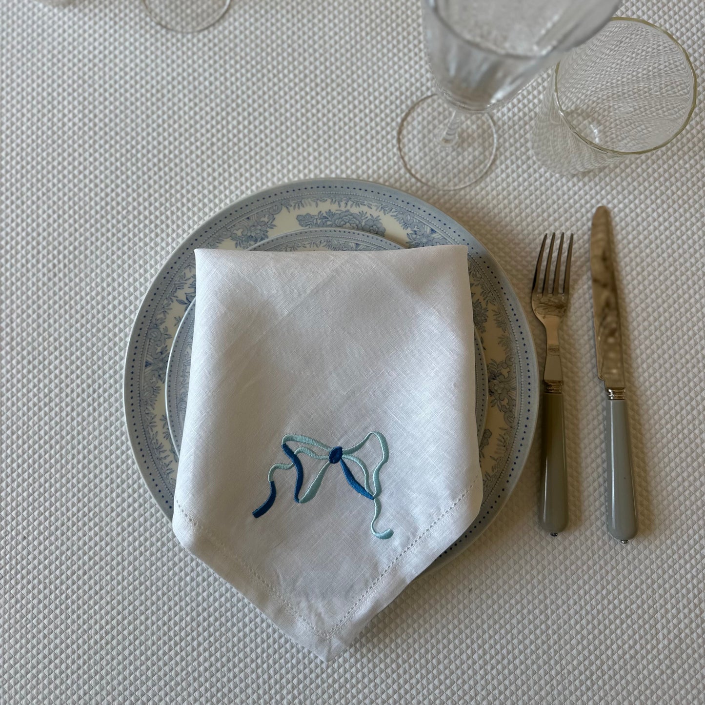 White linen napkin with a monogrammed blue bow