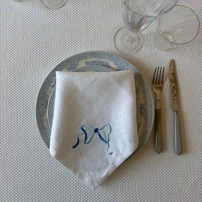 White linen napkin with a monogrammed blue bow