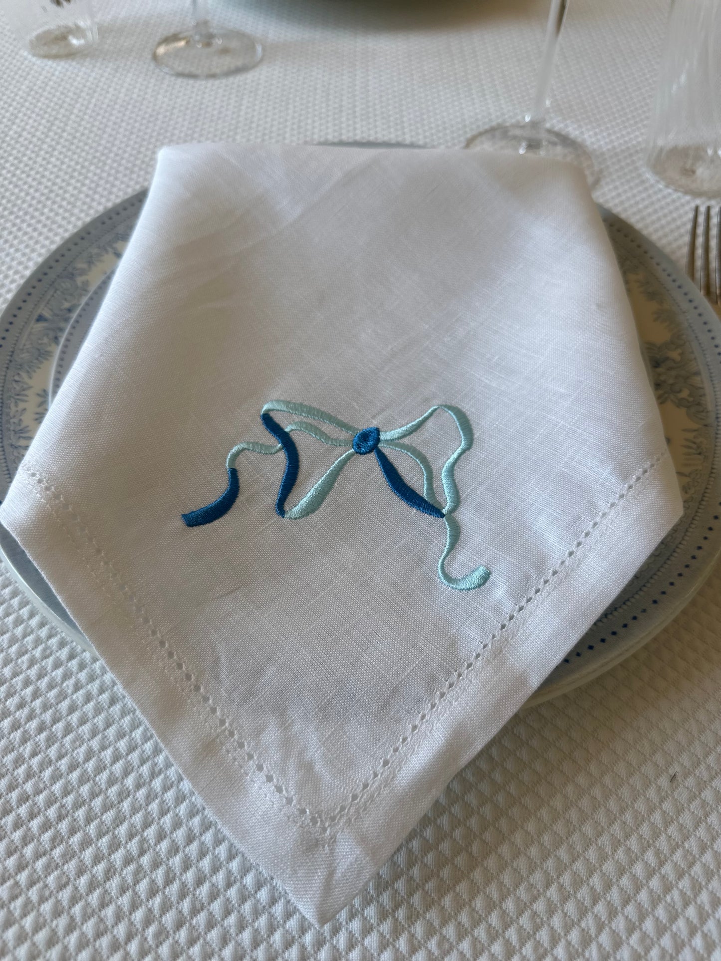 White linen napkin with a monogrammed blue bow